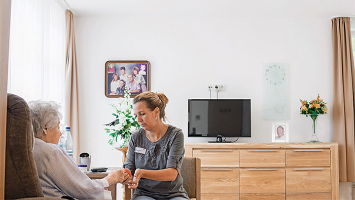 Un miembro del personal cuida de un paciente de la residencia geriátrica con la iluminación dinámica de las soluciones de Philips Healtcare Lighting