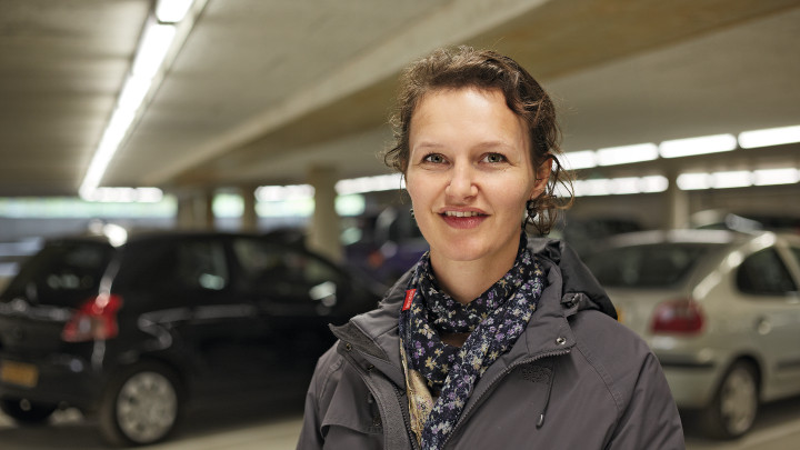  Mujer sonriendo frente a los coches en el aparcamiento de Eiteren, iluminado con Philips Lighting 