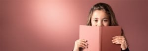"Jovencita asomada a un libro rosa sobre un fondo suave iluminado con LED, mostrando una iluminación cálida y uniforme para entornos de lectura confortables".