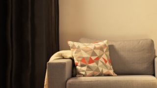 "Acogedora sala de estar con una moderna lámpara de mesa LED, que ilumina el sillón para dos personas gris y crea un ambiente cálido para relajarse en casa".