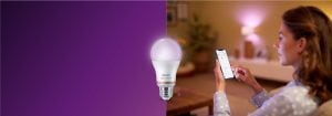 "Mujer que controla la iluminación LED inteligente mediante una aplicación de smartphone, creando un ambiente cálido en una acogedora sala con tecnología doméstica conectada".
