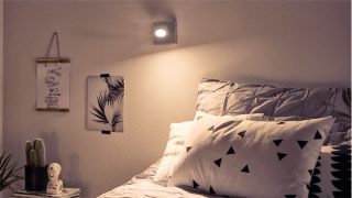 Elegante dormitorio con lámpara LED regulable que crea un ambiente acogedor, iluminando la ropa de cama geométrica y la decoración minimalista.